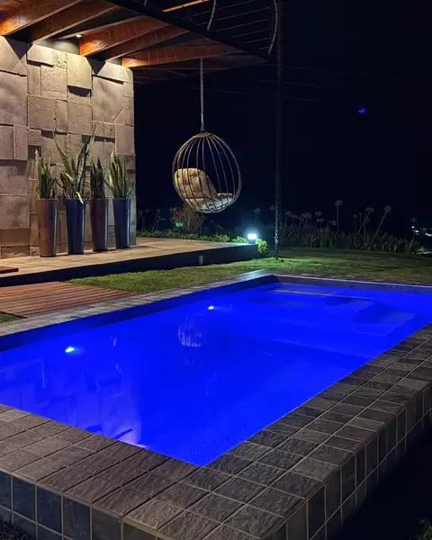 A piscina iluminada à noite, com a poltrona suspensa ao fundo