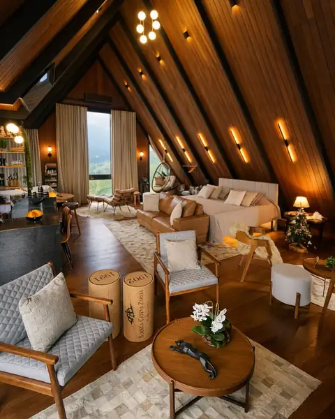 A sala sob o telhado em A de madeira, com a cama ao fundo